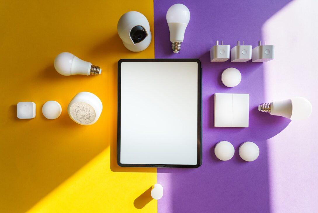 Top view of smart home devices and tablet on split yellow and purple background.