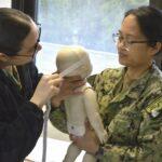 Two women practice infant cpr on a dummy.