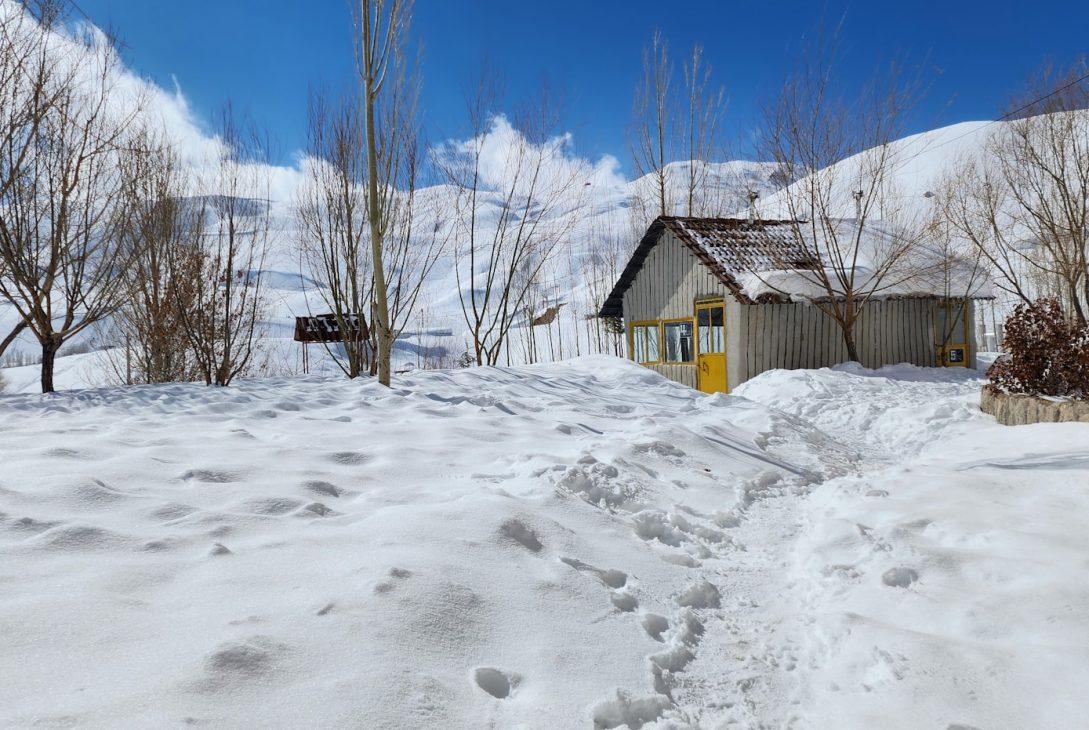 a snow covered road with a small house in the background