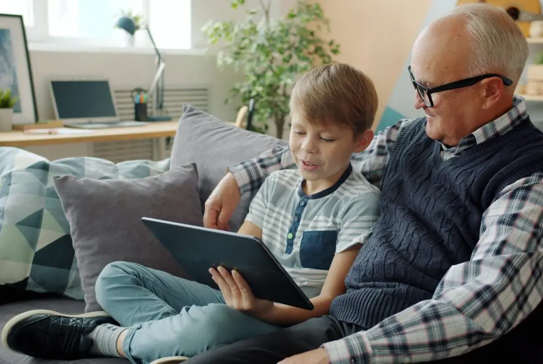 Grandfather and grandson looking at a tablet together.