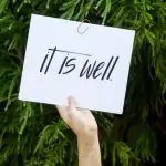 person holding white paper with it is well text