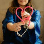 woman in scrubs holding heart shaped stethoscope