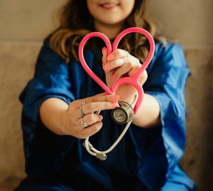 woman in scrubs holding heart shaped stethoscope