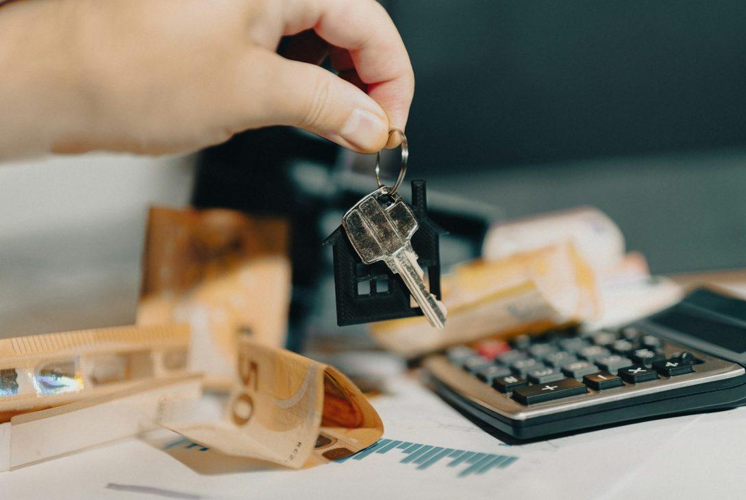 A person holding a house key in front of a calculator